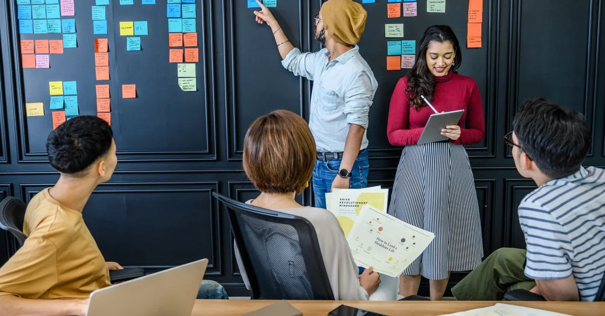 Un groupe divers collaborant avec des post-it dans un cadre de bureau moderne, favorisant la créativité et le travail d'équipe.