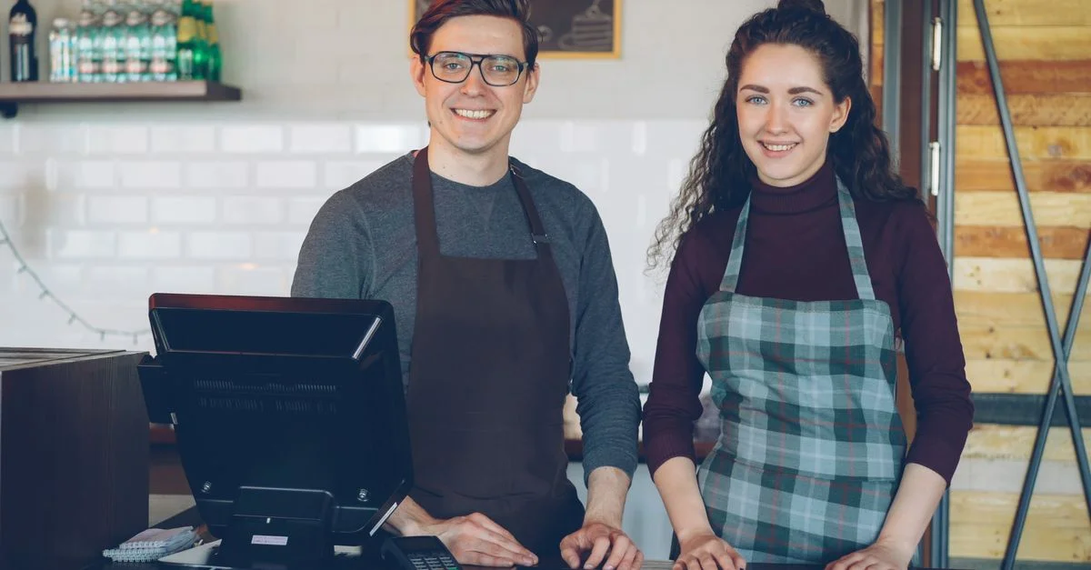 Le personnel du café sourit au comptoir, prêt à aider les clients.