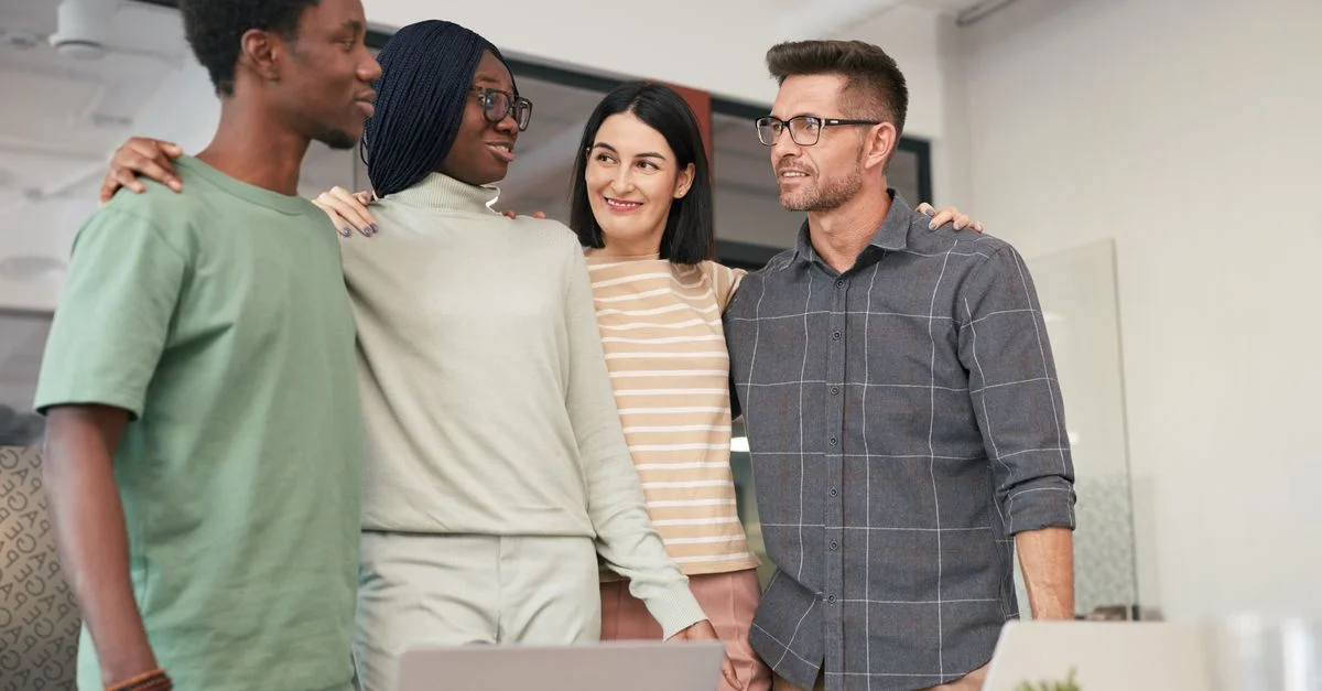 Quatre collègues divers partageant un moment de travail d'équipe et de collaboration dans un environnement de bureau.