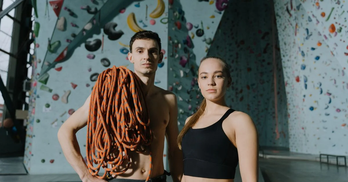 Deux grimpeurs dans une salle de sport, tenant des cordes d'escalade, prêts pour une aventure.