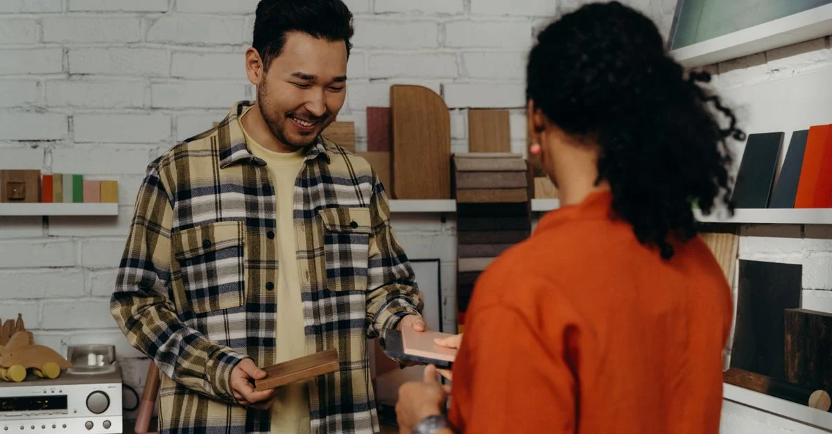 Un vendeur dans un showroom aide un client avec des échantillons de bois, présentant une sélection de matériaux.