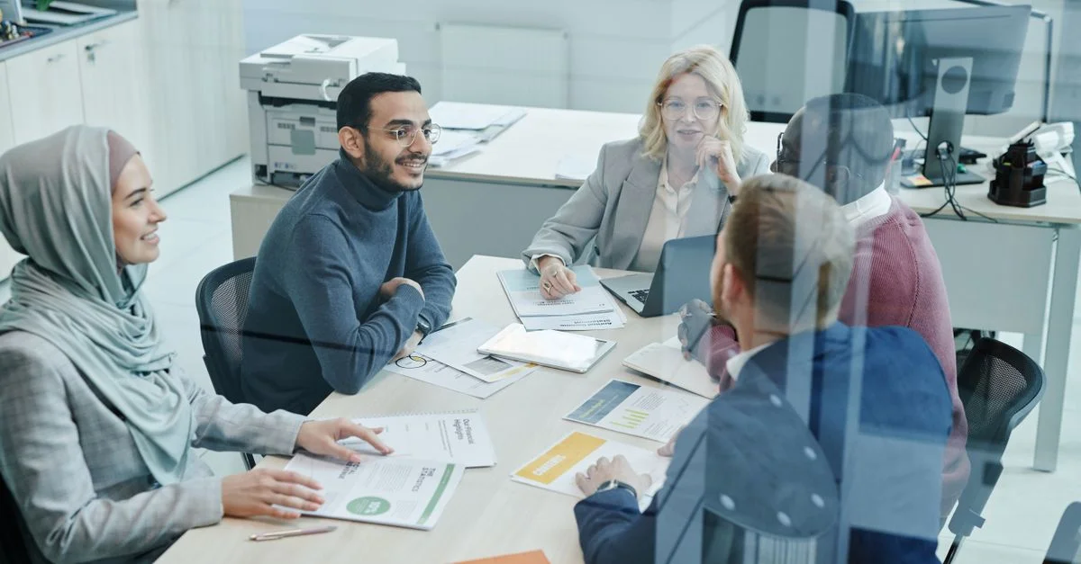 Un groupe diversifié de professionnels participant à une réunion dans un bureau moderne, favorisant le travail d'équipe et la collaboration.